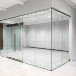 Frameless glass office cabin with sliding door.