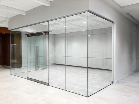 Frameless glass office cabin with sliding door.