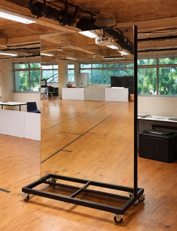 Large mirror mounted on a wheeled metal frame indoors