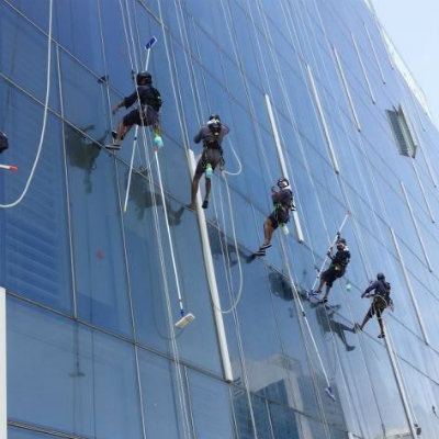 Multiple workers rope-cleaning a glass skyscraper facade