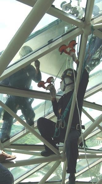Workers cleaning glass panels on a structural frame