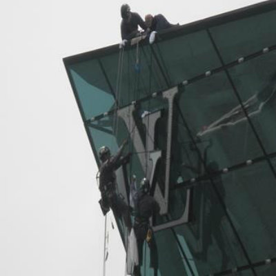 Workers suspended by ropes cleaning a glass building facade